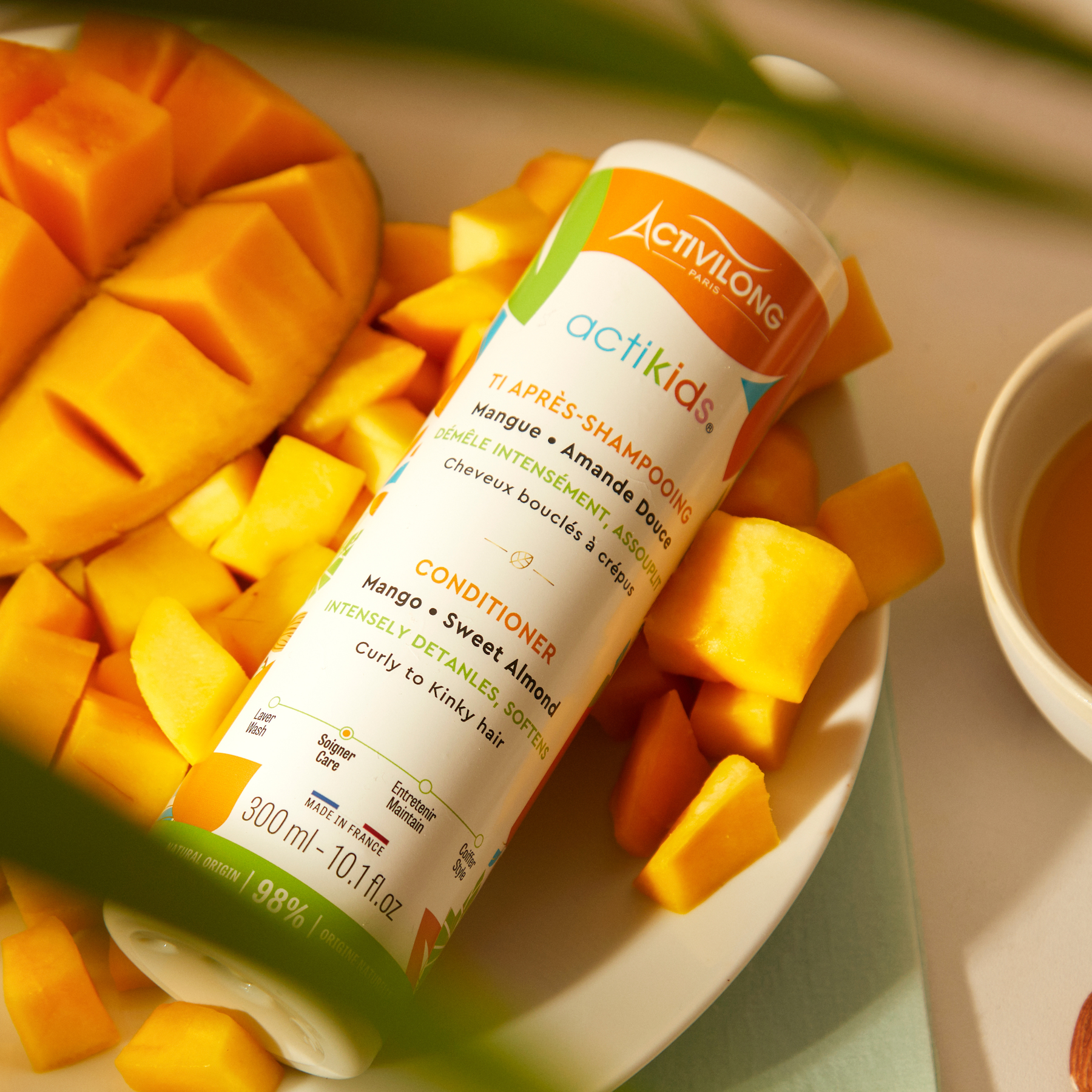 ACTIVILONG ACTIKIDS Conditioner Après-Shampoing 250ml bottle by Afro Beauty Store with mango pieces on a plate