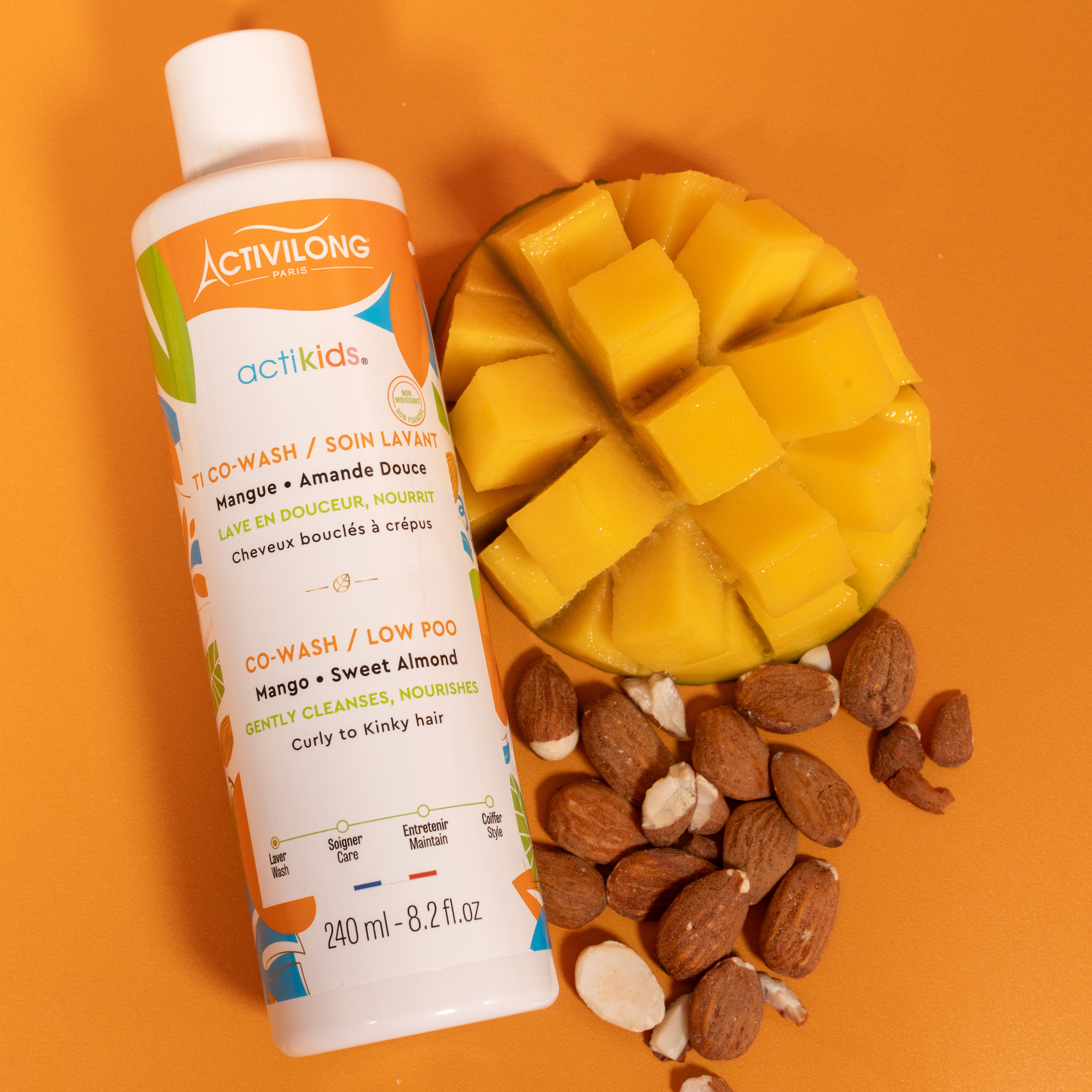 ACTIVILONG ACTIKIDS TI Co-Wash Soin Lavant 240ml bottle by Afro Beauty Store with a sliced mango and almonds on an orange background