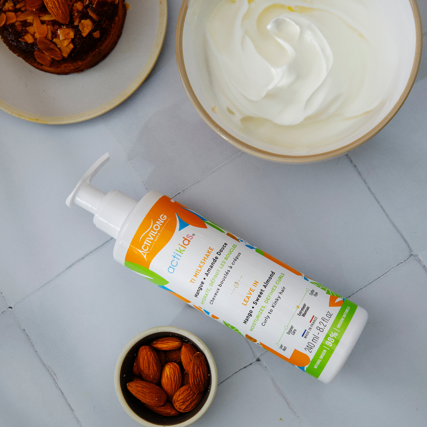 ACTIVILONG ACTIKIDS Ti Milkshake Leave-In 250ml bottle by Afro Beauty Store on a tiled surface with almonds and a dessert.
