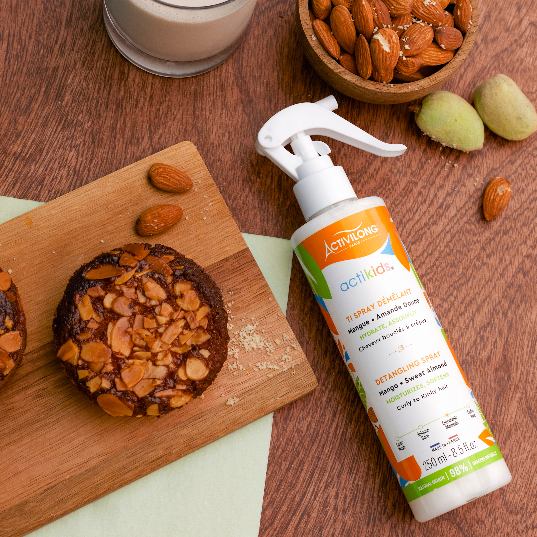 ACTIVILONG ACTIKIDS Ti Spray Démêlant 250ml bottle by Afro Beauty Store on a wooden surface with cookies and almonds.