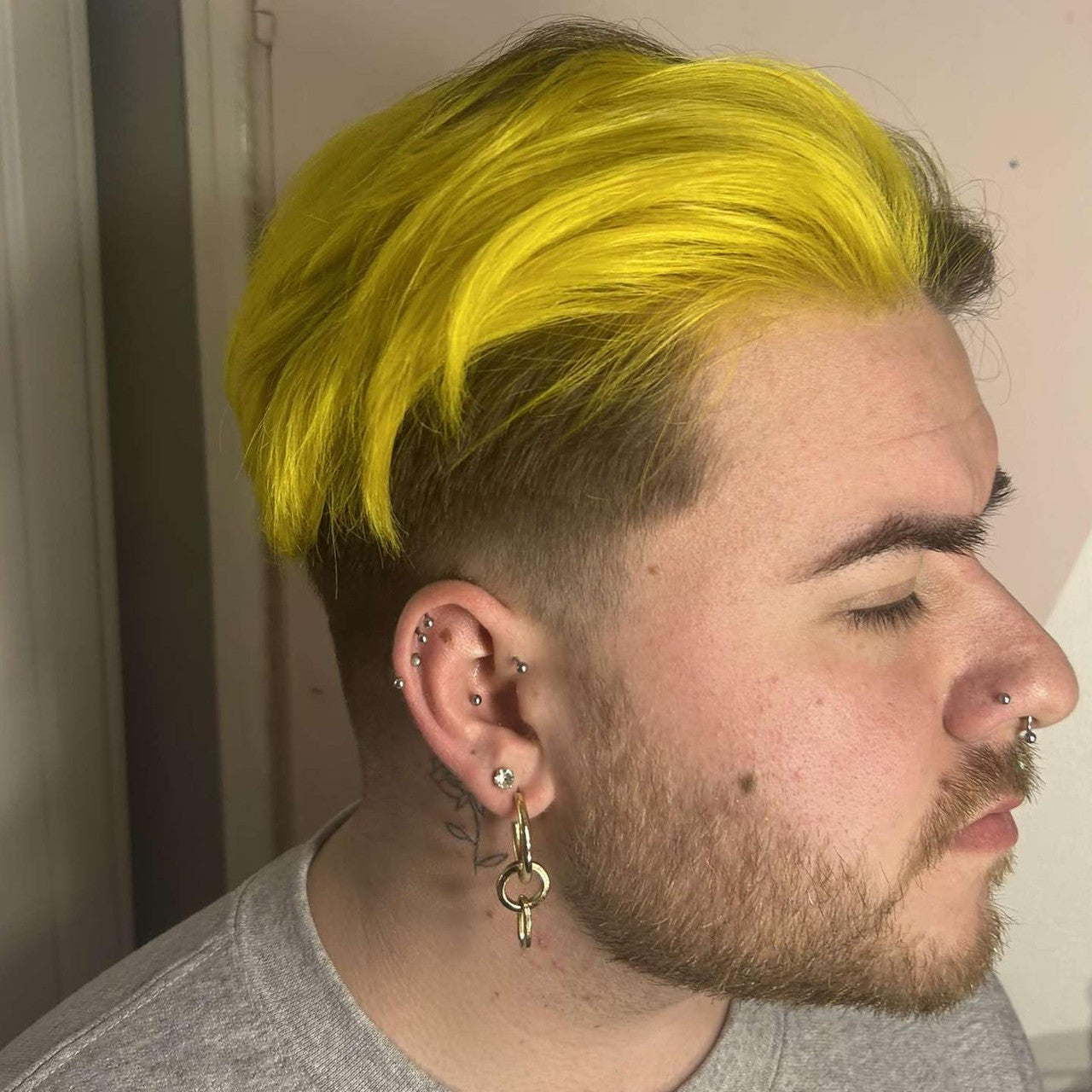 Crazy Color's Person with bright yellow hair and multiple piercings, wearing a gray shirt by Afro Beauty Store