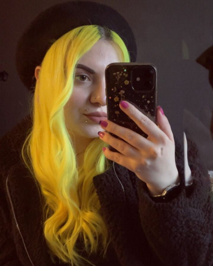Crazy Color's Person with yellow hair holding a phone in a dark setting by Afro Beauty Store