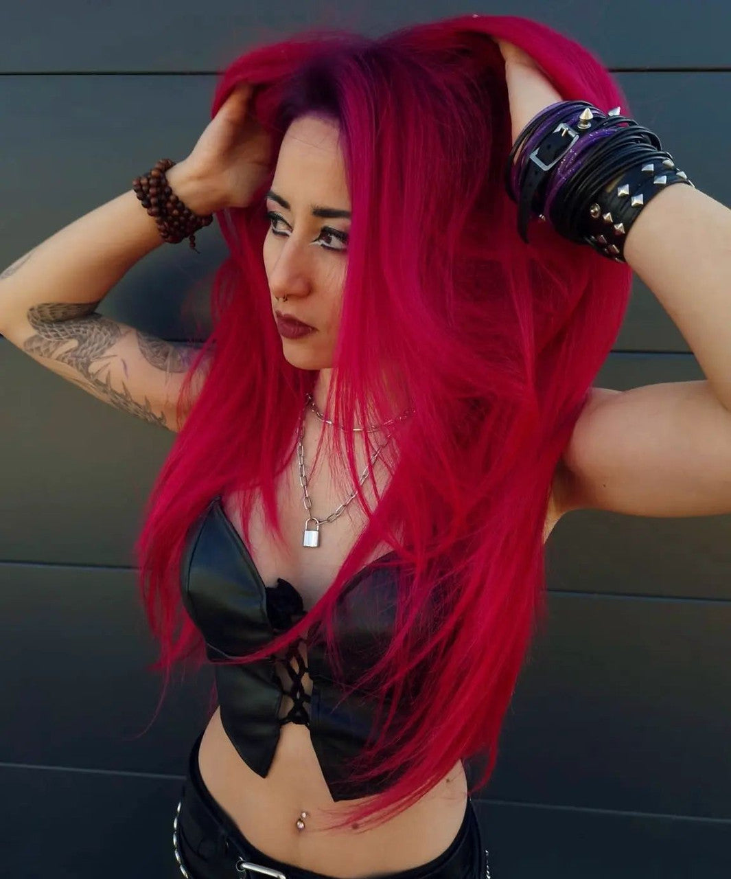 Crazy Color's Person with vibrant red hair and tattoos posing against a dark background by Afro Beauty Store