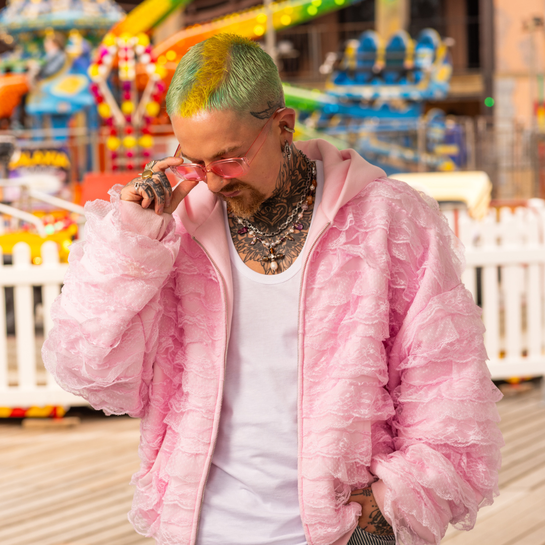 Crazy Color's person wearing a pink jacket and sunglasses at an amusement park by Afro Beauty Store