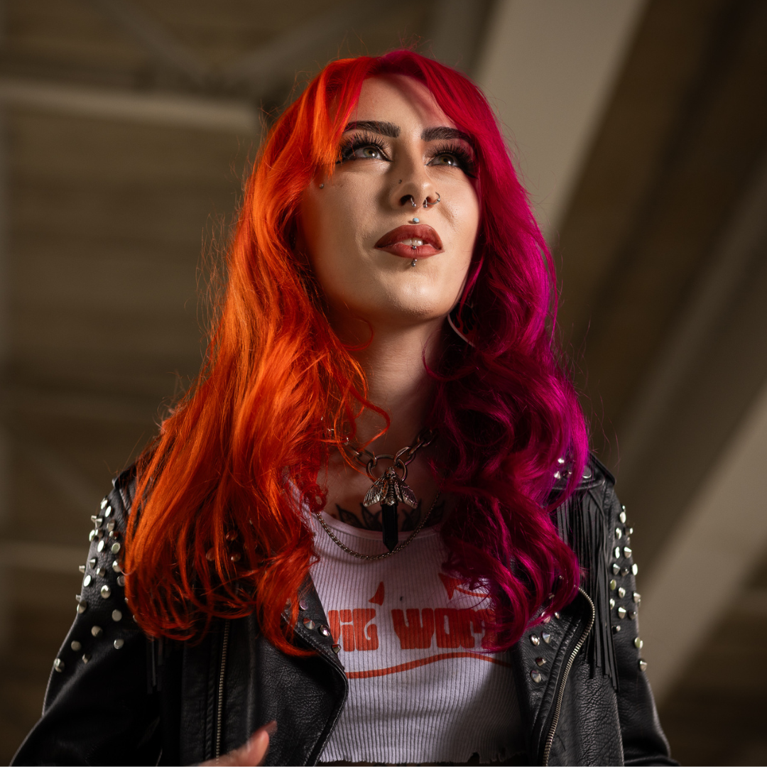 Crazy Color's Person with vibrant red and pink hair wearing a black leather jacket and white t-shirt with text - Afro Beauty Store
