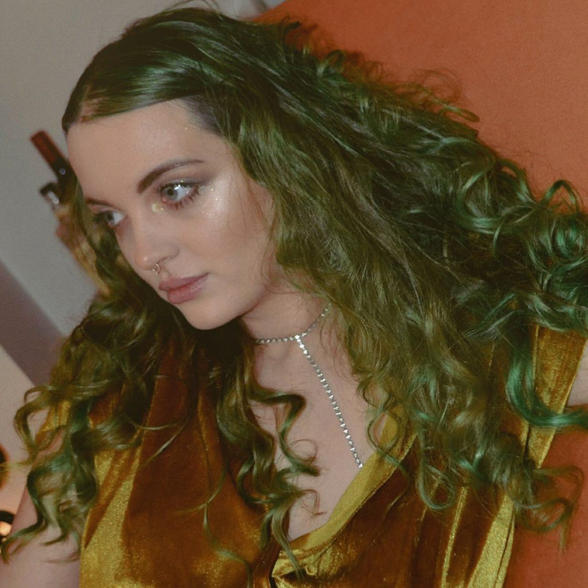 Crazy Color's person with wavy hair and a gold top against an orange background by Afro Beauty Store