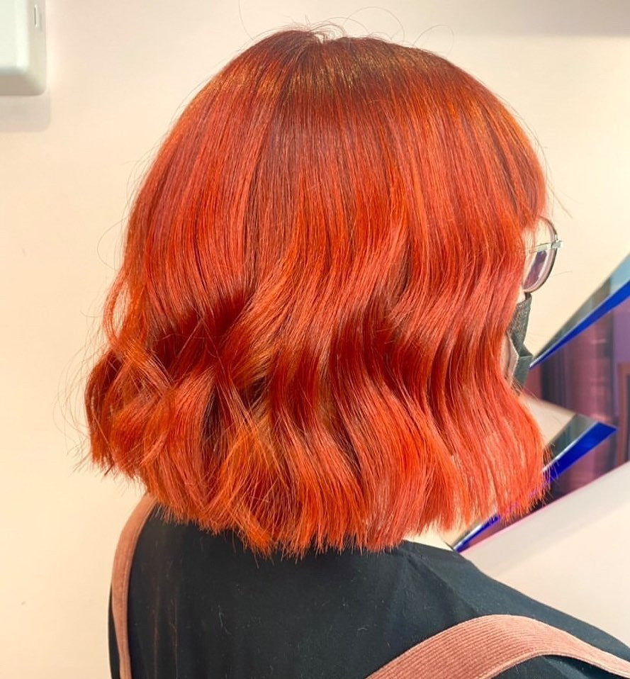 Crazy Color's Person with vibrant orange-red hair in a salon setting by Afro Beauty Store