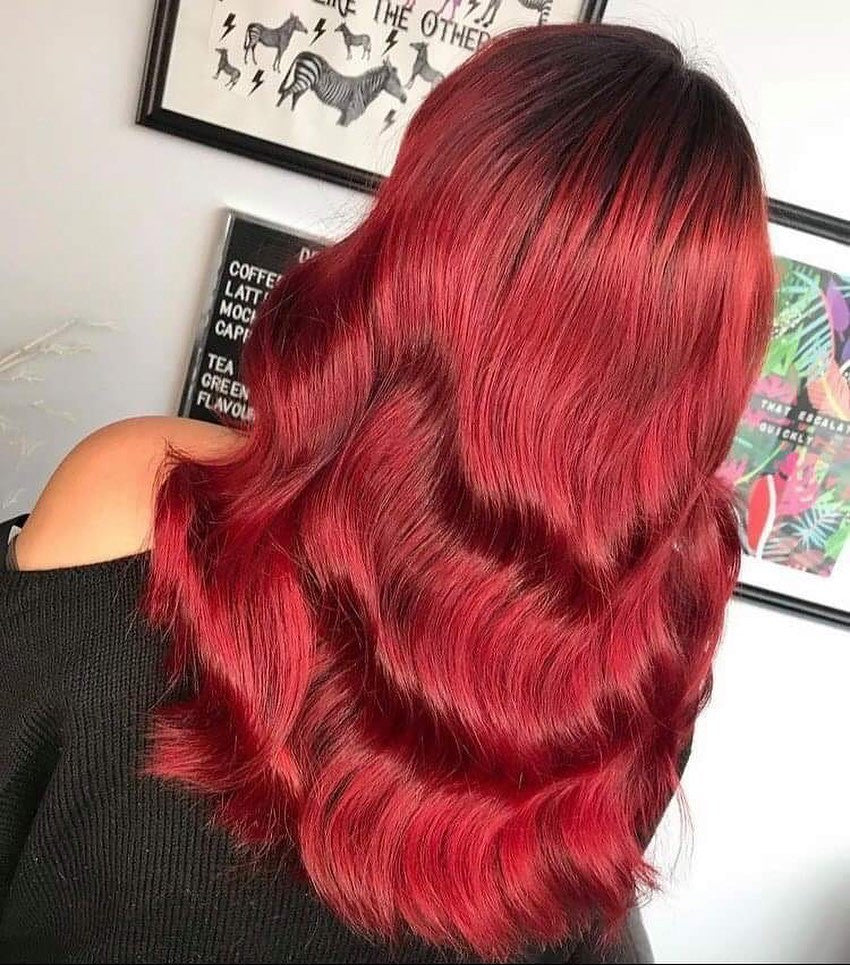 Crazy Color's person Red hair with wavy texture in front of a white wall with framed pictures by Afro Beauty Store