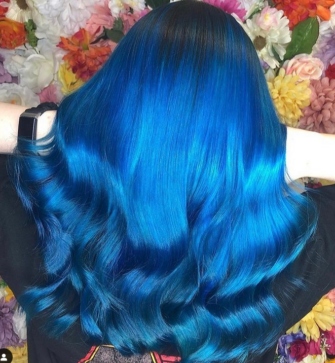 Crazy Color's Person with vibrant blue hair in front of a floral background by Afro Beauty Store
