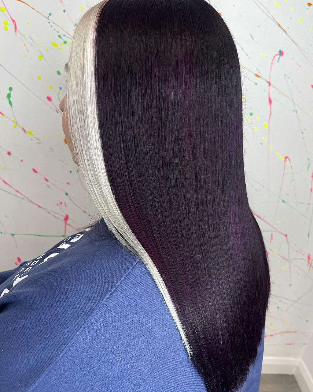 Crazy Color Person wearing a black and white hairpiece against a colorful splatter-painted wall by Afro Beauty Store