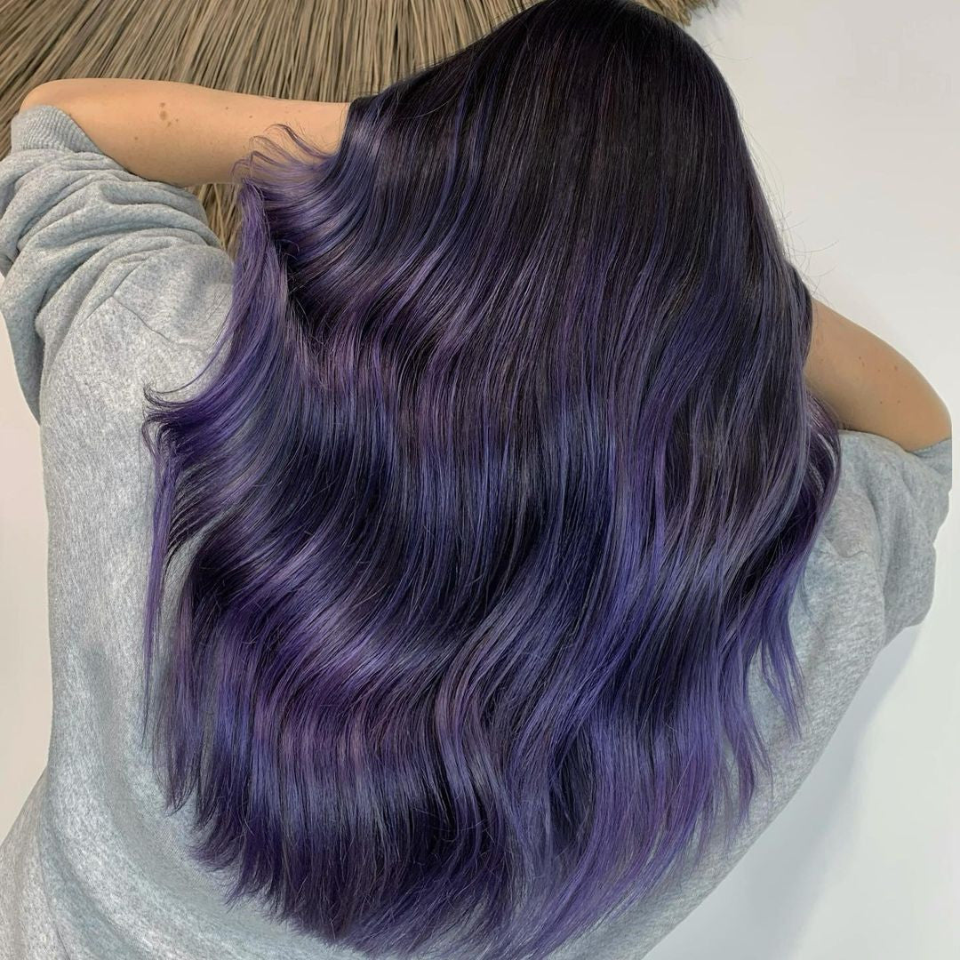 Crazy Color's Person with purple hair styled in loose waves, wearing a light gray long-sleeve shirt by Afro Beauty Store