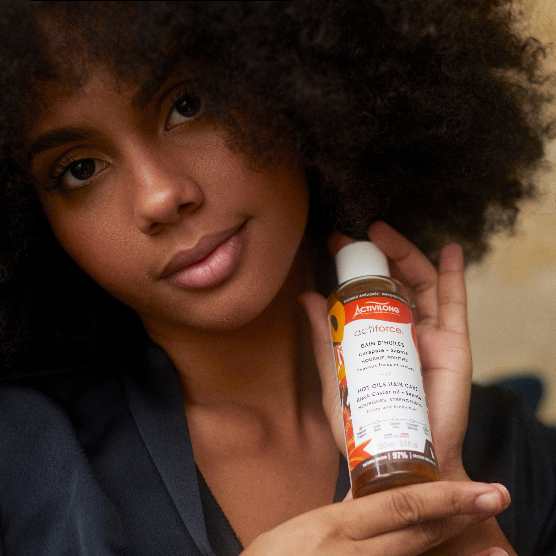 Woman holding an ACTIVILONG ACTIFORCE Bain d'Huile 130ml Bottle by Afro Beauty Store close to her hair