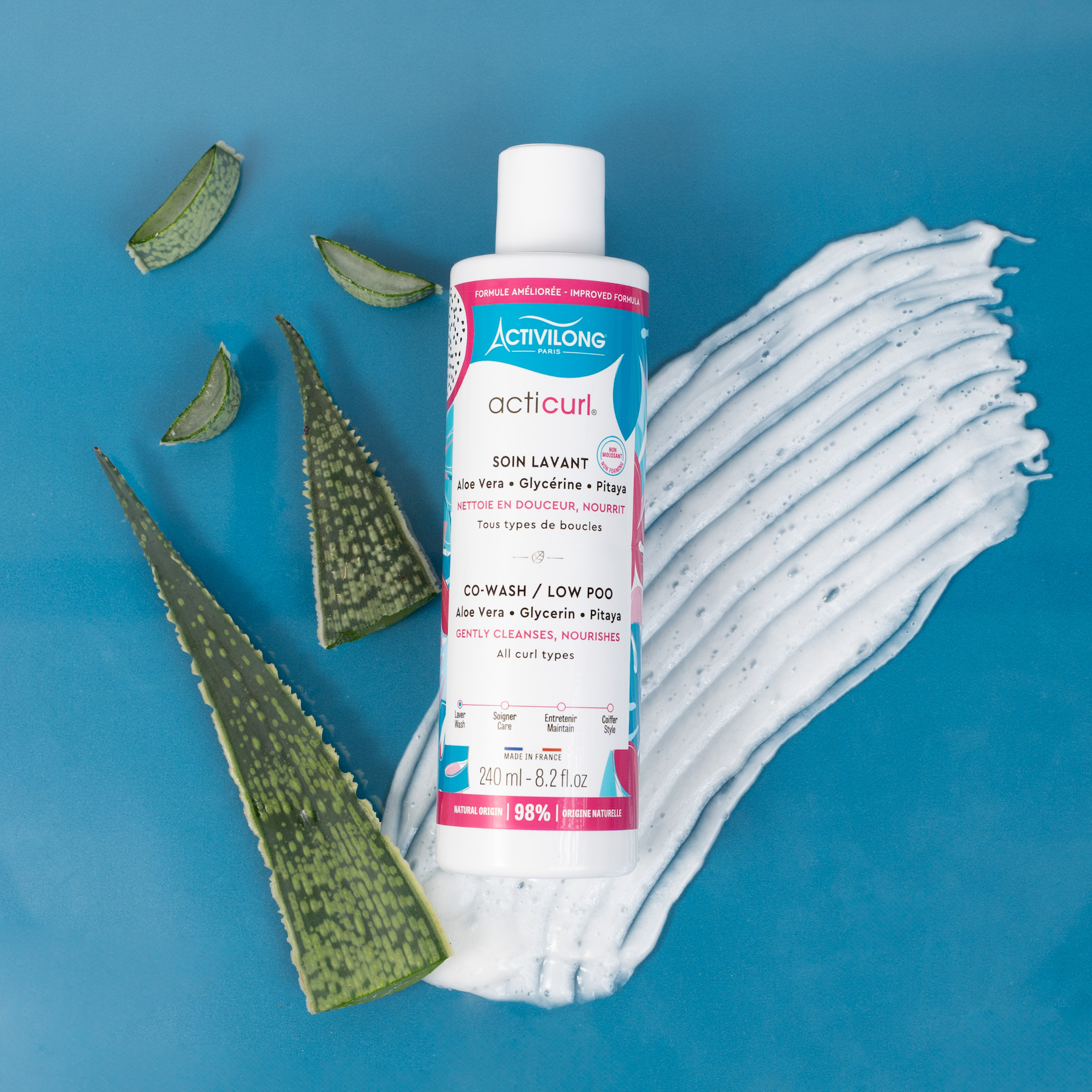Bottle of ACTIVILONG ACTICURL Co-Wash 240ml by Afro Beauty Store with aloe vera leaves on a blue background