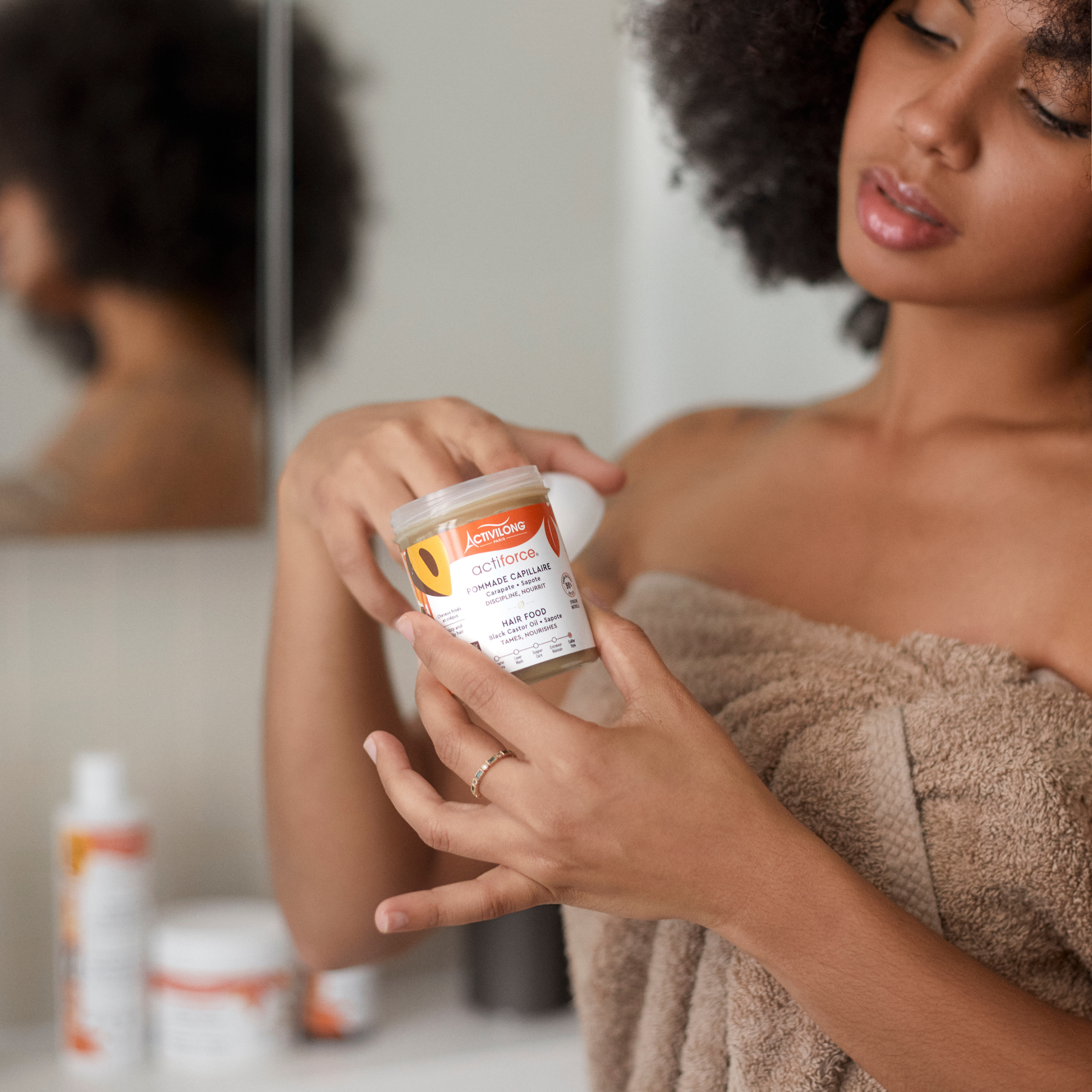 Woman holding an ACTIVILONG ACTIFORCE Pommade Fortifiante 100ml container by Afro Beauty Store