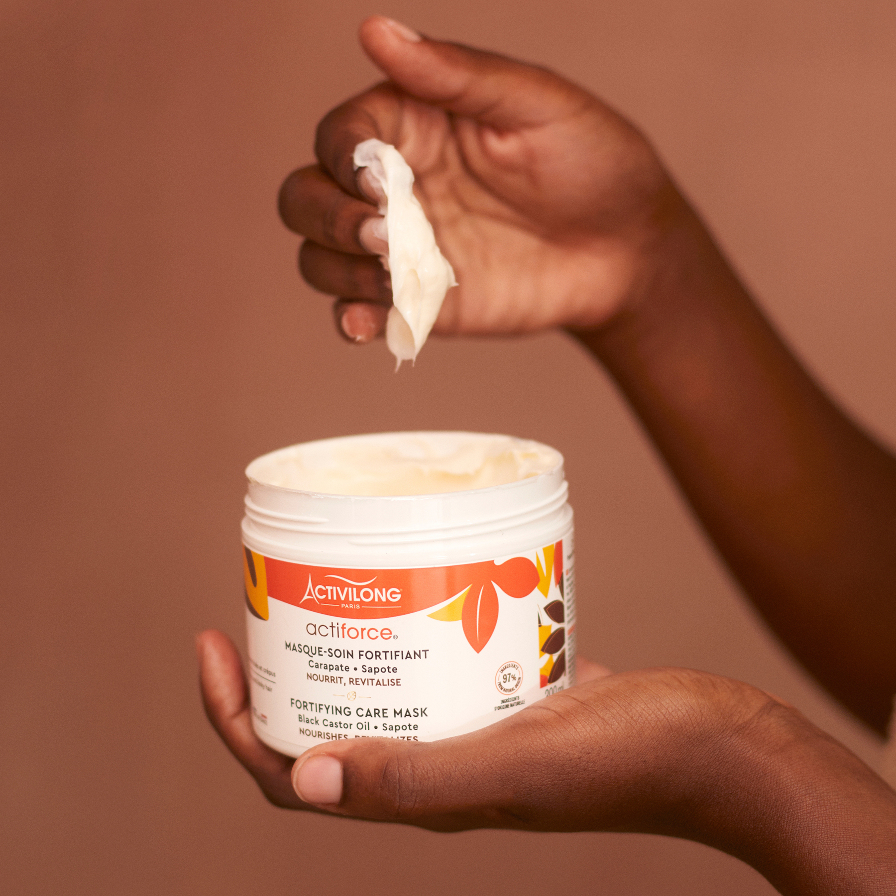 Hand holding a ACTIVILONG ACTIFORCE Masque 300ml by Afro Beauty Store with a brown background