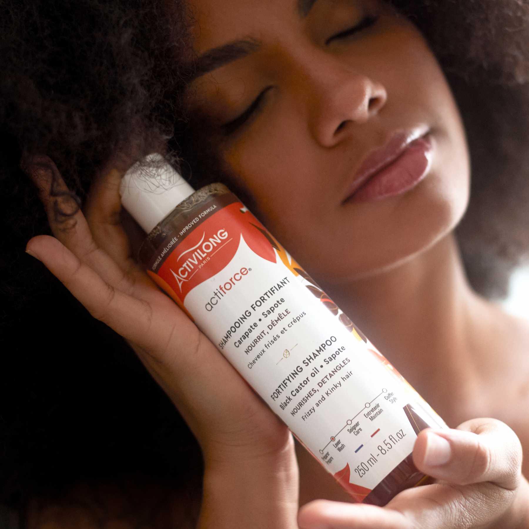 Person holding an ACTIVILONG ACTIFORCE Fortifiant Shampoing 250ml bottle by Afro Beauty Store close to their hair