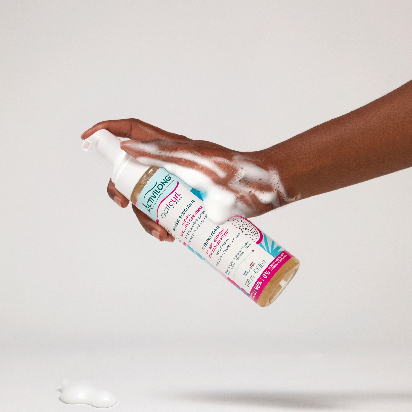 Hand holding a ACTIVILONG ACTICURL EXPERT Mousse Bouclante 200ml bottle by Afro Beauty Store with a white background
